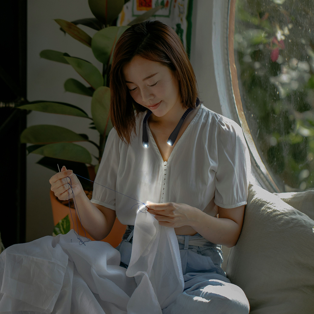 woman sewing with neck light