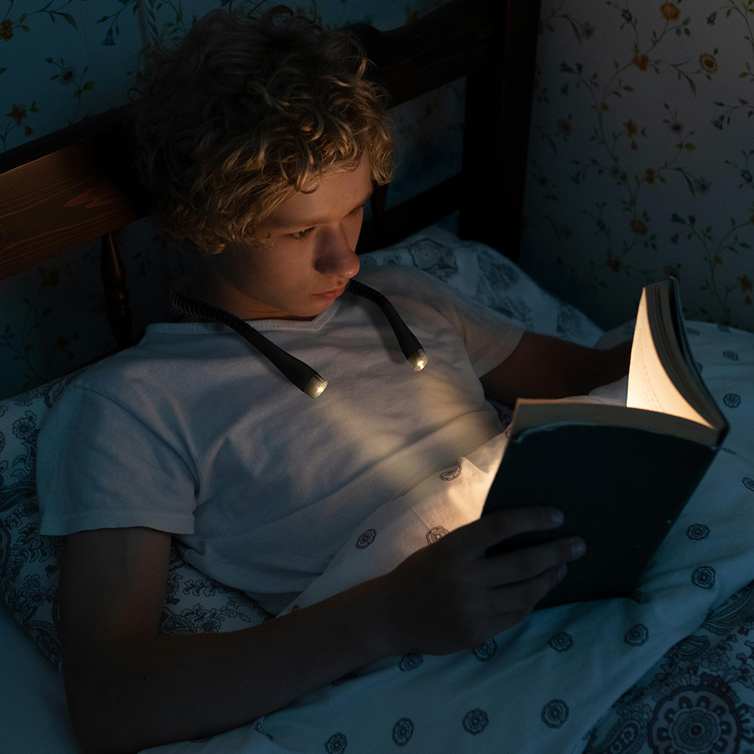 boy reading at night with neck light