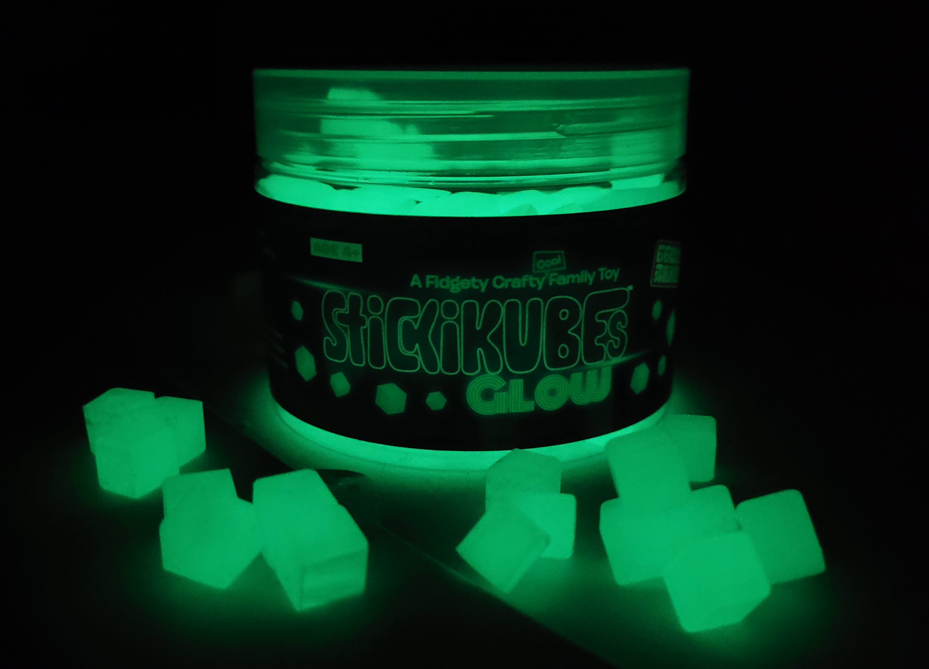 Container of Slickikubes Glow with glowing green cubes on a black background
