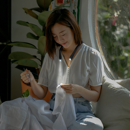 woman sewing with neck light