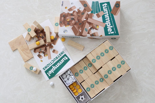 Wooden tumbling block game with pieces and instructions on a light surface